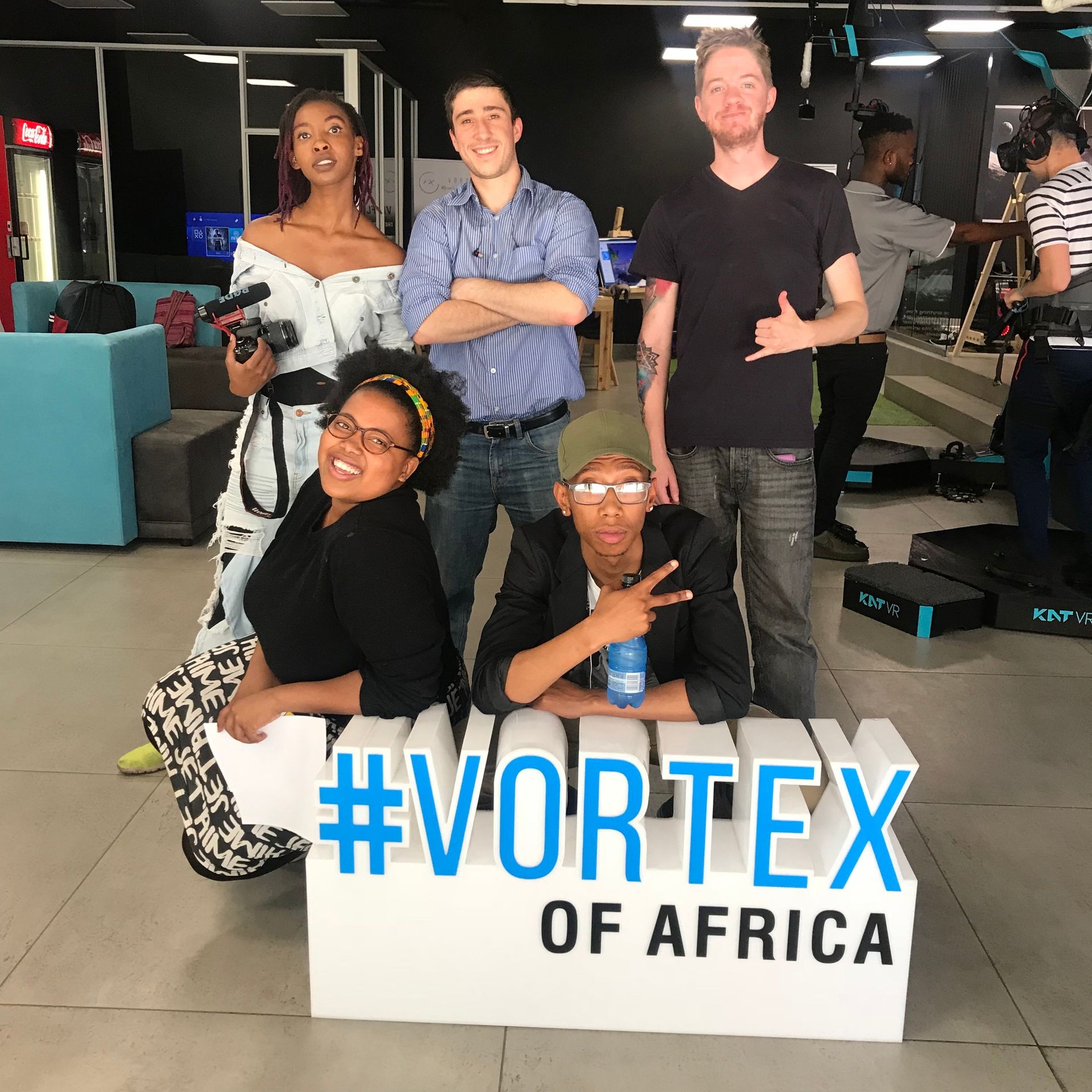 Group of people posing behind a sign reading '#Vortex of Africa' in a studio setting.